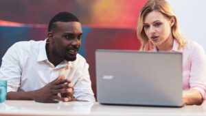 Man and woman discussing work displayed on laptop